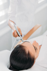 attractive woman receiving facial treatment in spa center