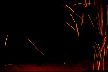 Fire sparks in the air near the forge. Close-up on a black background