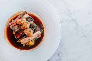 Braised pork belly in brown sauce with vegetables, modern Chinese cuisine in fine dining restaurant.