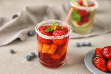 Glass of refreshing summer cocktail with fruits and berries on table