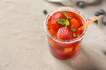 Glass of refreshing summer cocktail with fruits and berries on table