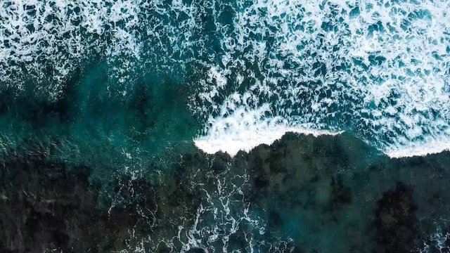beautiful slow motion wave on the rocky beach in tenerife while a long oceanic foam is coming. aerial footage slow motion landscape and water waves with nobody. vacation outdoor