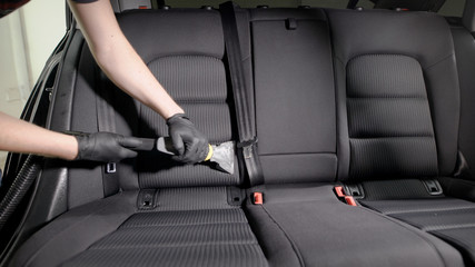 Faceless employee carefully vacuuming car seat