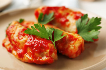 Stuffed cabbage leaves in tomato sauce on plate, closeup