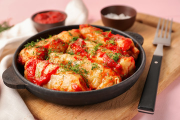 Pan with stuffed cabbage leaves in tomato sauce on wooden board