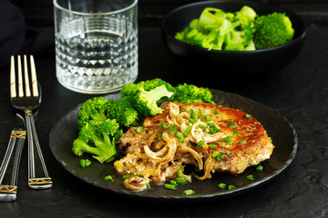 Fried pork steak with broccoli and onion sauce.