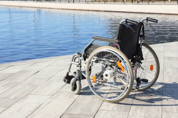 Empty modern wheelchair near river on embankment