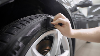 Close up shot of a man wiping tire after cleaning on car washing station.