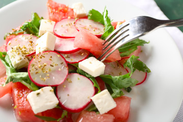 Eating of tasty salad with watermelon, feta and radish, closeup