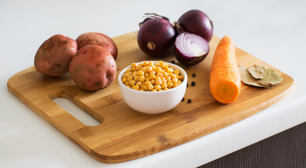 Ingredients for vegetable soup. Ingredients for pea soup: potatoes, carrots, onions, garlic, peppers and peas on a wooden board. Rustic style.