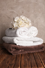 Fototapeta na wymiar Stack of soft clean towels with flowers on wooden table