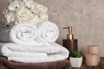 Stack of soft clean towels with flowers on wooden table