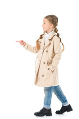 adorable kid in beige coat pointing somewhere, isolated on white