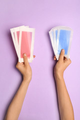 Woman holding different wax strips on color background