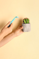 Woman holding razor and cactus on color background