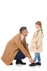 father and daughter in beige coats looking at each other, isolated on white