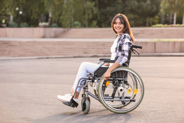 Fototapeta na wymiar Happy young woman in wheelchair outdoors