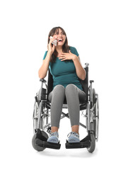 Young woman in wheelchair talking by mobile phone on white background