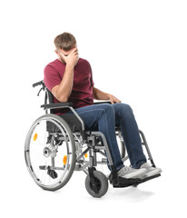 Depressed young man in wheelchair on white background