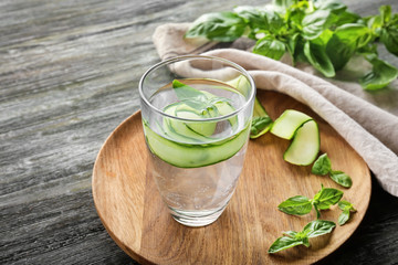 Glass of cucumber infused water on wooden table