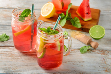 Mason jars of tasty watermelon lemonade on light wooden table