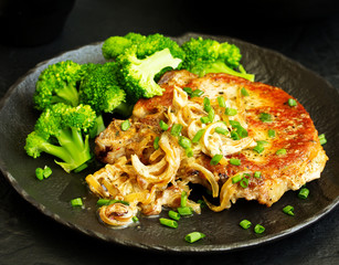 Fried pork steak with broccoli and onion sauce.