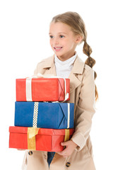 smiling kid in beige coat holding gifts, isolated on white