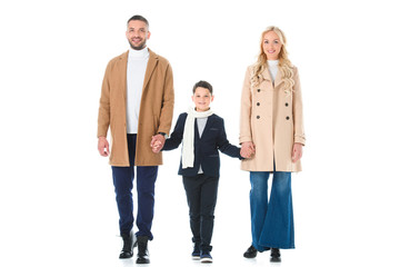 parents in beige coats and son holding hands, isolated on white