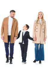parents in beige coats holding hands with son, isolated on white
