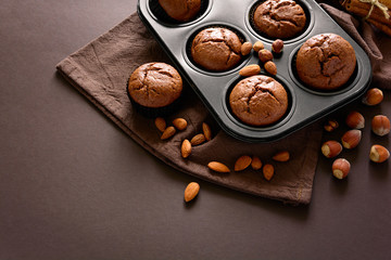 Homemade chocolate muffins (brownies) with cinnamon, almonds and hazelnuts on brown paper background