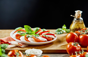 Tomatoes, cheese and basil on wooden board