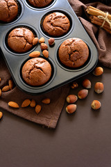 Homemade chocolate muffins (brownies) with cinnamon, almonds and hazelnuts on brown paper background