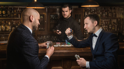 men play poker at the bar