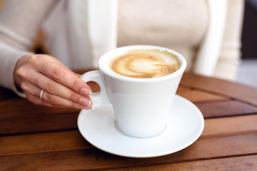 Girl in white suite drinking a cup of coffee