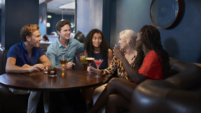 Group Of Young Friends Relaxing In Bar Together On Night Out