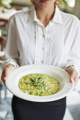 Close Up Of Waitress Holding Plate Of Pea And Mint Risotto In Restaurant 
