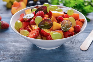 Bowl with delicious fruit salad on color wooden table