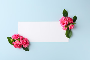 Beautiful blooming flowers and empty sheet of paper on color background