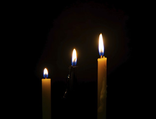 Candle burning brightly close up on the black background