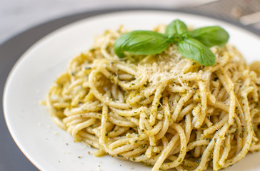 Cooked spaghetti pasta on a plate with basil pesto and Parmesan cheese, Italy food, healthy concept, vegetarian