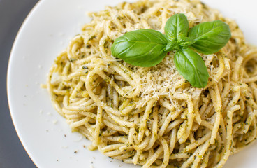 Cooked spaghetti pasta on a plate with basil pesto and Parmesan cheese, Italy food, healthy concept, vegetarian
