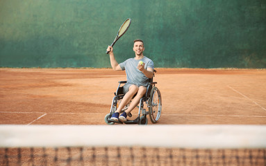 Young man in wheelchair playing tennis on court