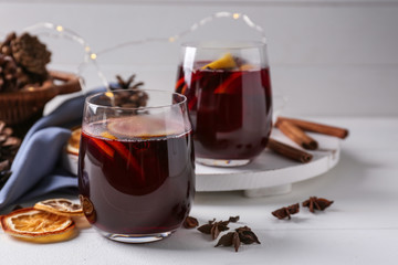 Glasses of delicious hot mulled wine on light table