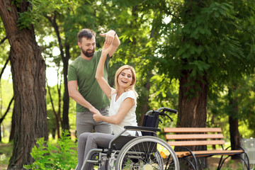 Beautiful woman in wheelchair with man dancing outdoors