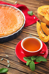 Cup of tea and tasty pumpkin pie on wooden table