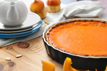 Baking dish with tasty pumpkin pie on wooden table