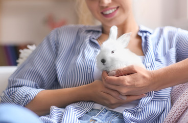 Beautiful young woman with cute rabbit at home, closeup