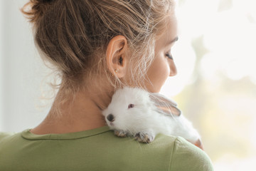 Beautiful young woman with cute rabbit at home