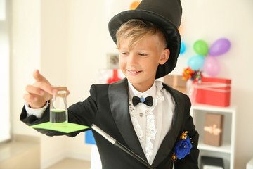 Cute little magician showing trick indoors