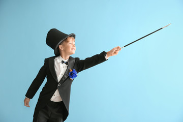 Cute little magician showing trick on color background